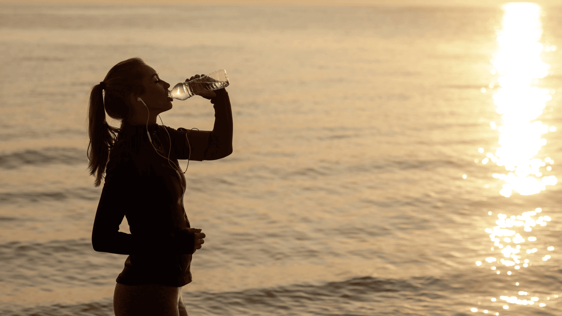 young-sportswoman Young Sporty Woman Drinking Water on the Beach